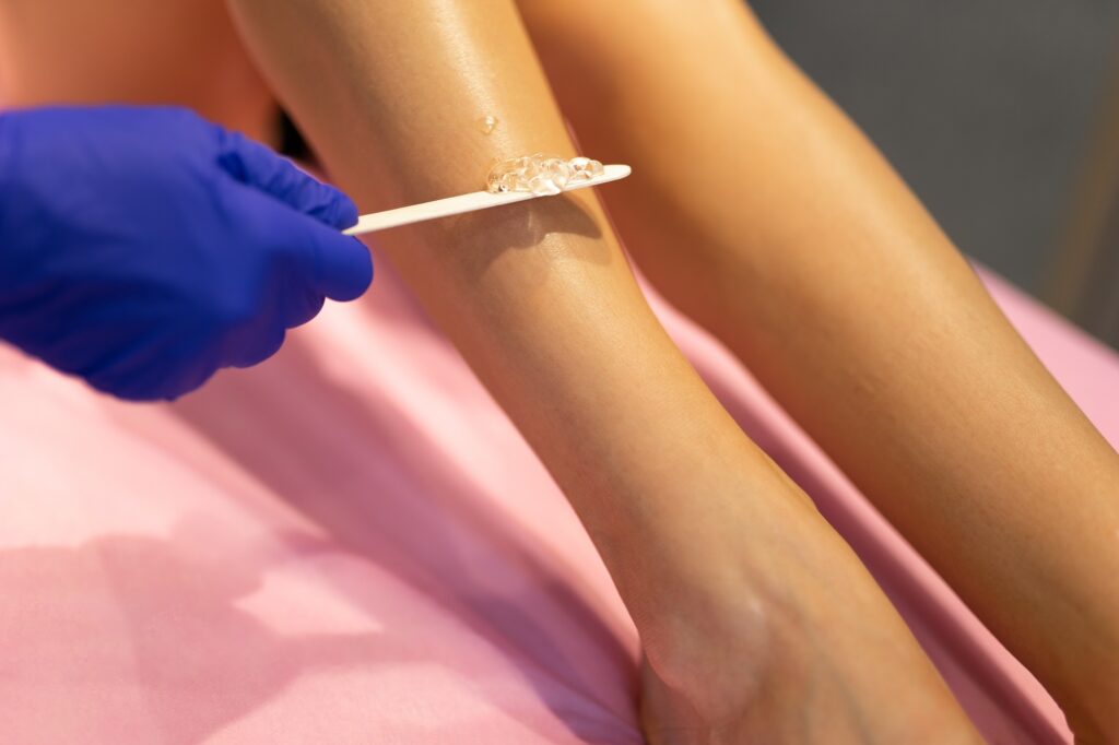Beautician applies laser depilation gel to the patient's legs